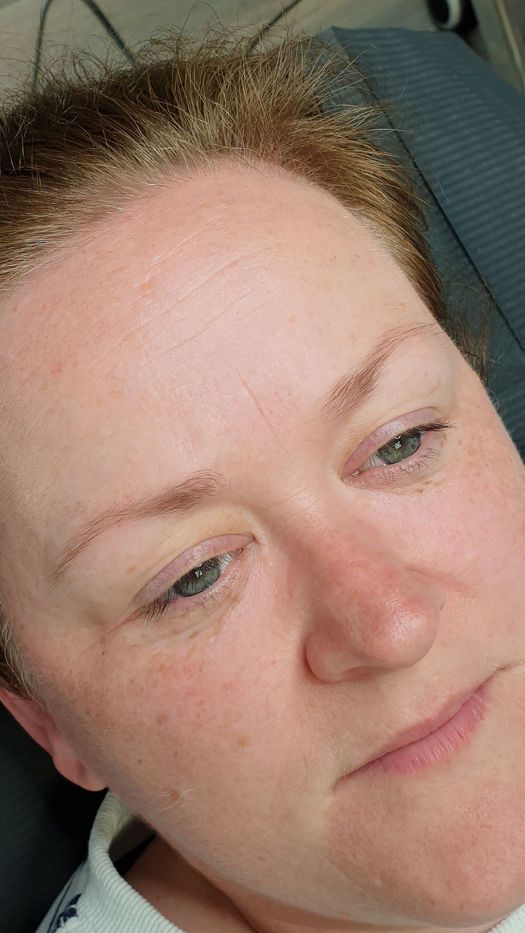 A woman in a black top and earrings, displaying her semi-permanent makeup results for a gallery in Cork - before
